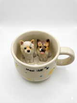 Ceramic mug with two miniature dog figurines inside the cup.